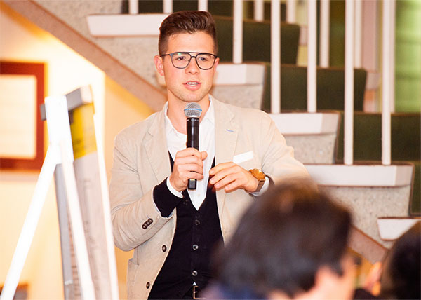 college student in business casual clothes speaking with microphone to the group at the event