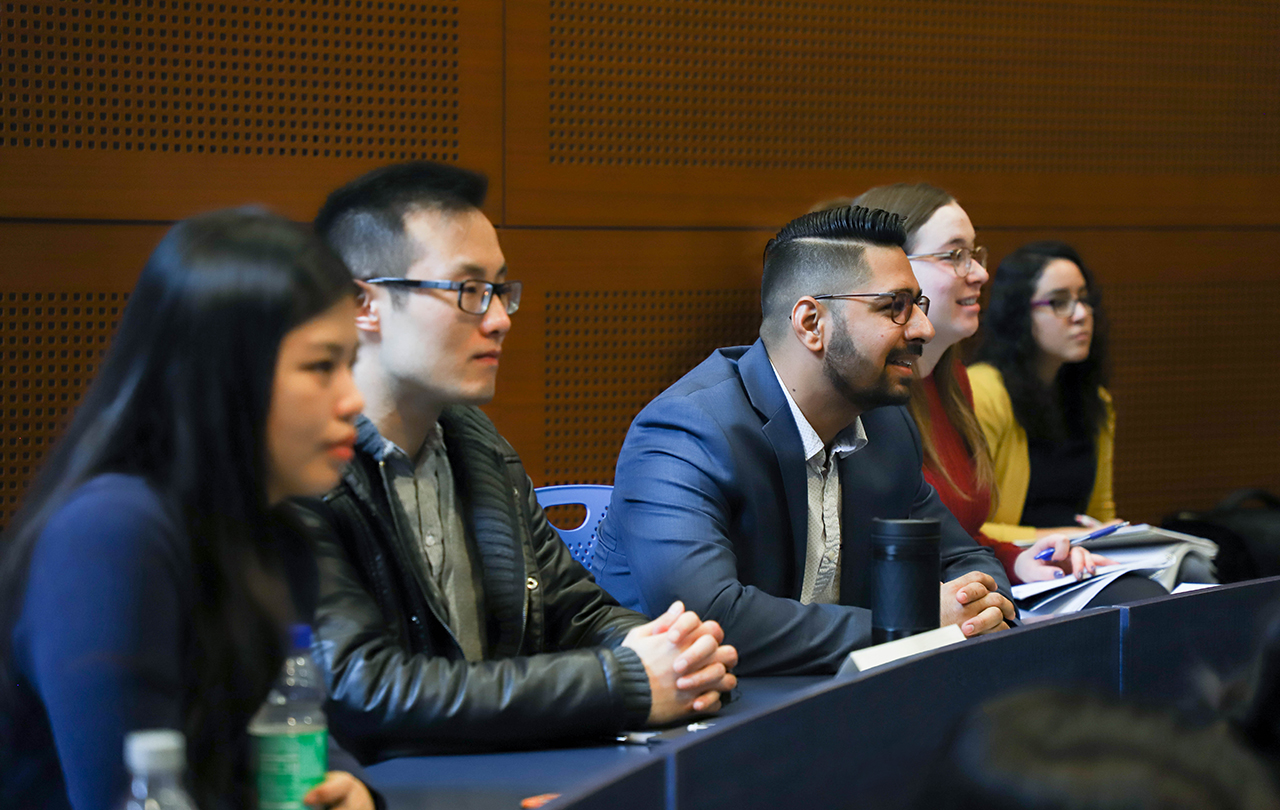 five students in business attire sitting in class smiling