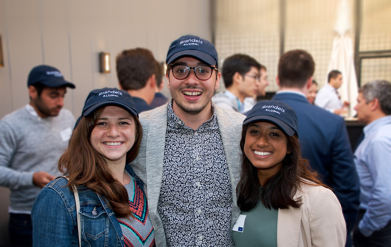 Three 2018 alumni wearing Brandeis IBS alumni hats