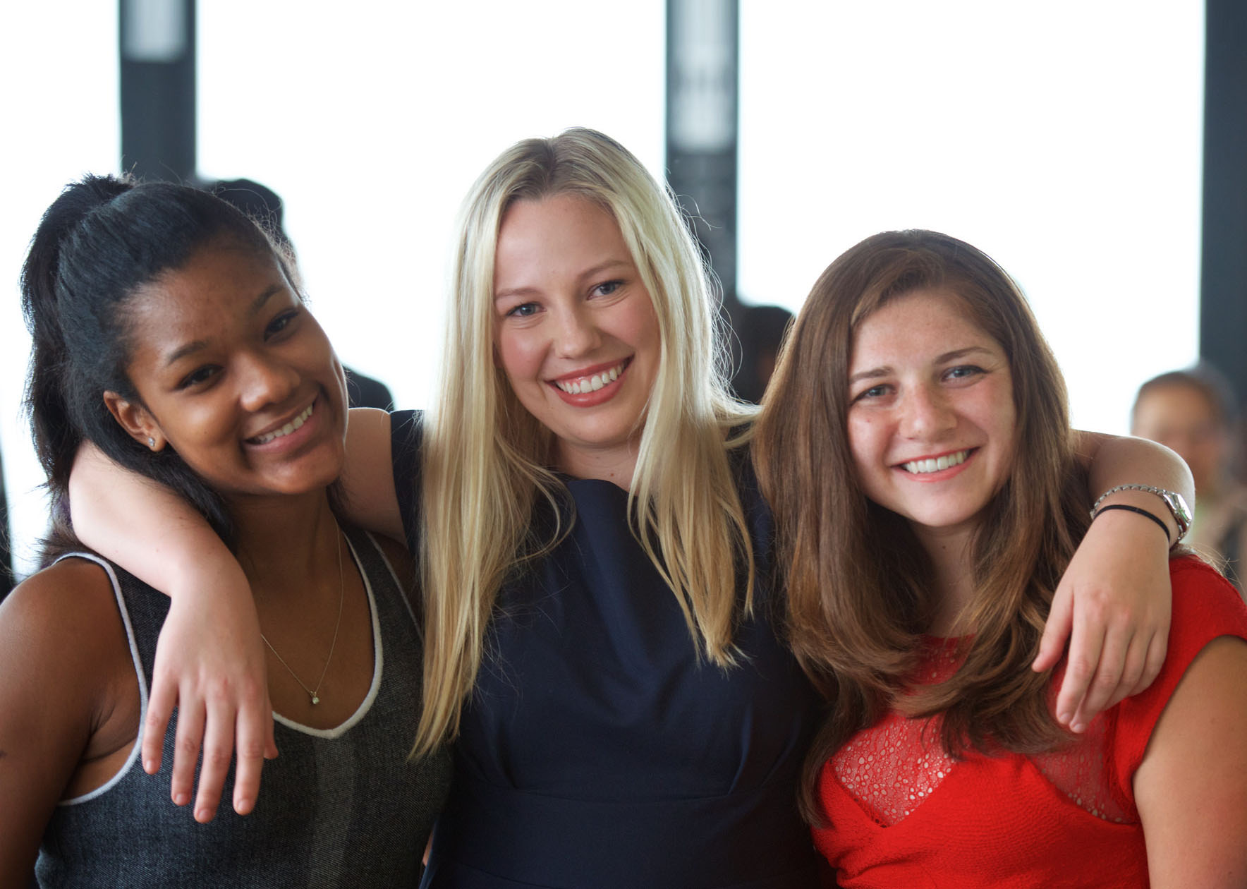 3 females in their lower twenties in formal attire at a reception