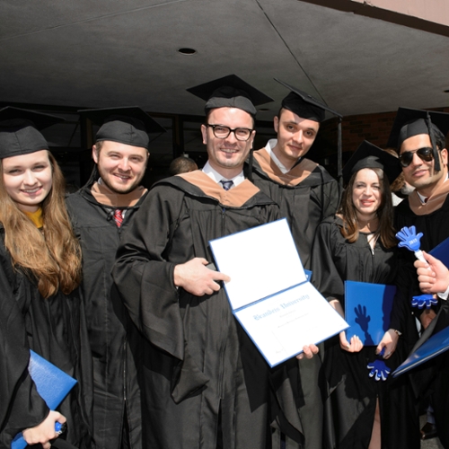 Students gather outside Levin Ballroom and show off their diplomas.
