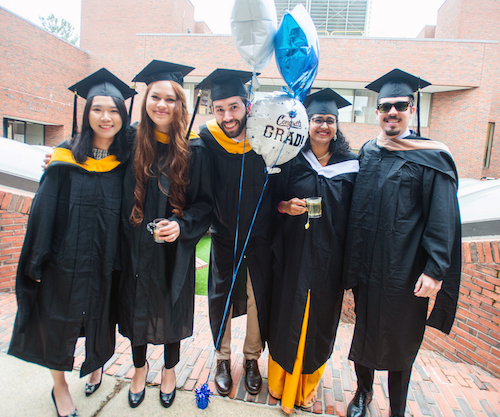 students posing together outside after graduating 