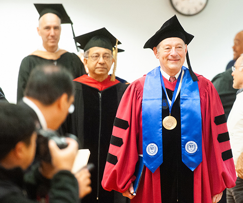 Interim Dean Peter Petri walking into graduation