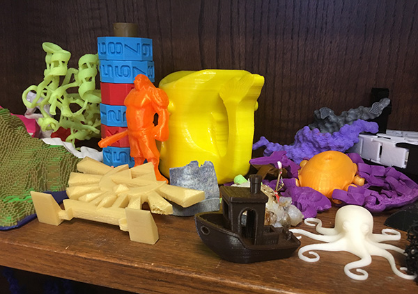 Student-printed objects on display in the MakerLab include a Minecraft scene, DNA molecules and a water pitcher.