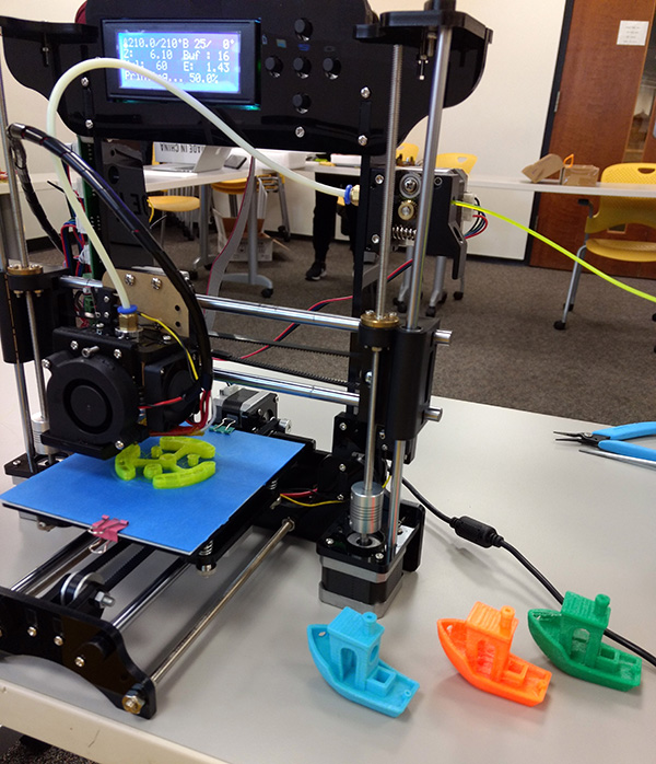 One of the 3D printers used by the Brandeis IBS students alongside some plastic boats it printed.