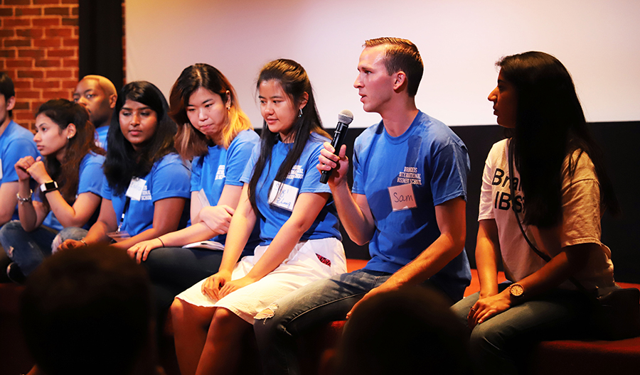 A student holds a microphone during a panel discussion.