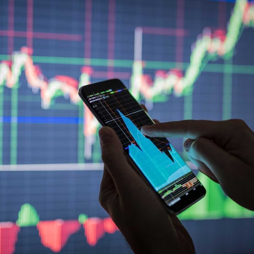 A phone showing a volatile graph in front of a volatile line graph.