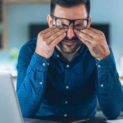 A man rubbing his eyes while working at home.