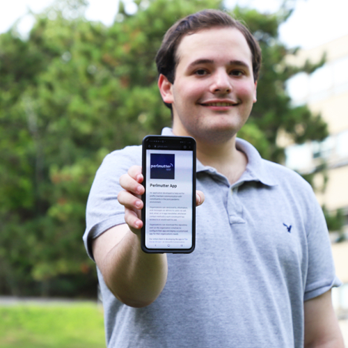 Adam Fleishaker holds a cell phone that displays the Perlmutter App.