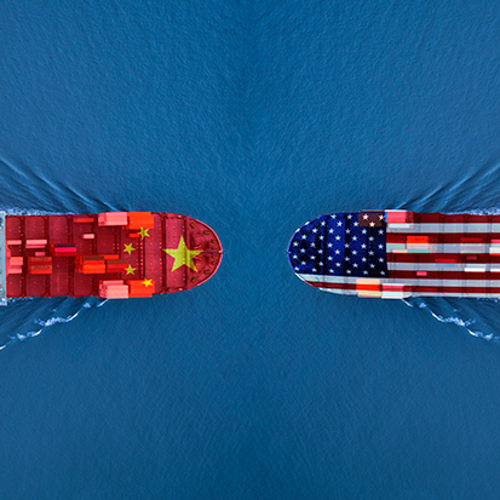A graphic of two freight ships in the ocean, one with the American flag superimposed on the bow and the other with the Chinese flag.