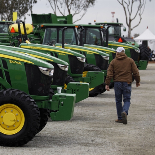 A farmer walks past a line of new tractors.