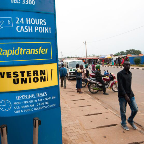 People walking past a Western Union sign.