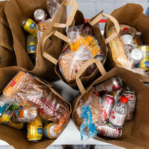 A shot looking down into several paper bags full of groceries.