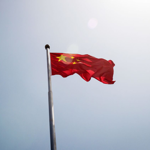 The Chinese flag set against a gray sky.