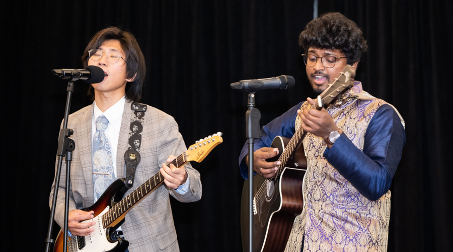 Two students play a song on guitar on stage.