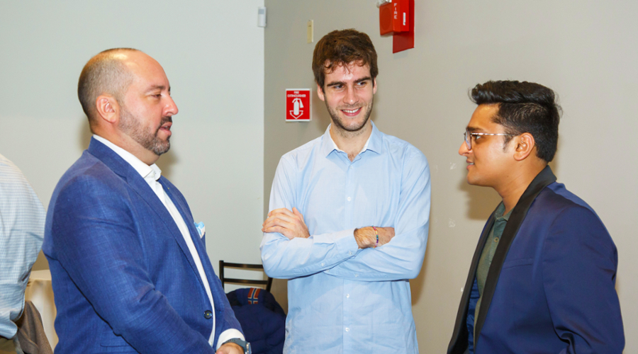 Two students chat with Prof. Aldo Musacchio.