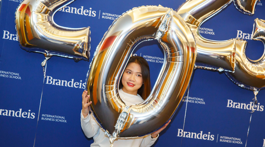 A student smiles while looking through the 0 in a 2023 balloon.