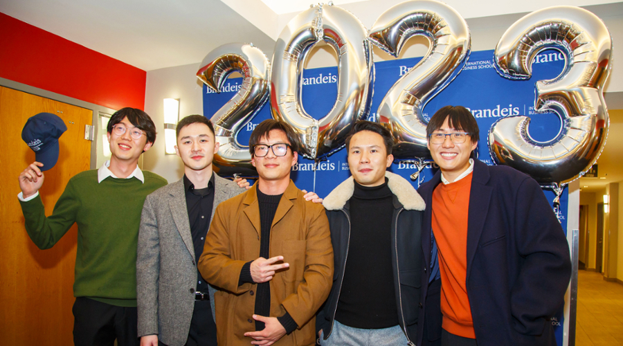 A group of students smile and pose during the mid-year graduation dinner.