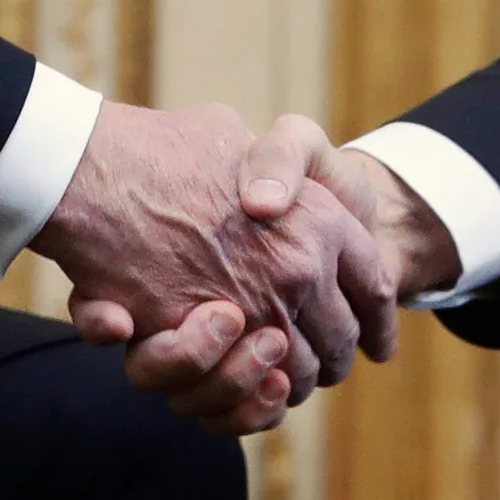 A closeup of two men in business suits shaking hands.