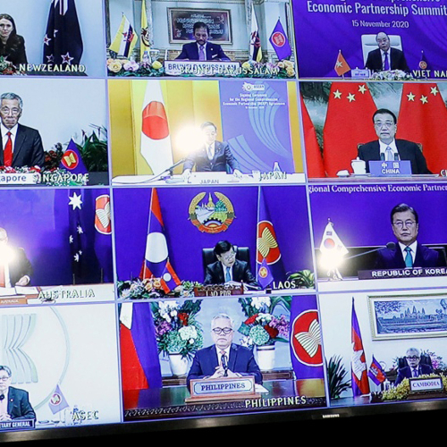 An image of several Asian leaders at desks arrayed in a grid on a large screen.