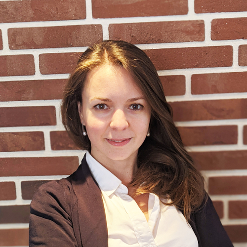 A portrait of Anna Kovalenko posing in front of a red brick wall.