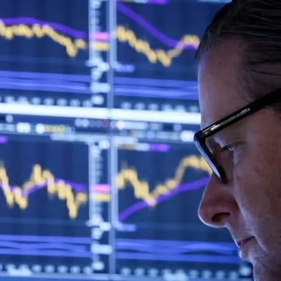 Image of an economist in front of a bank of screens depicting stock projections