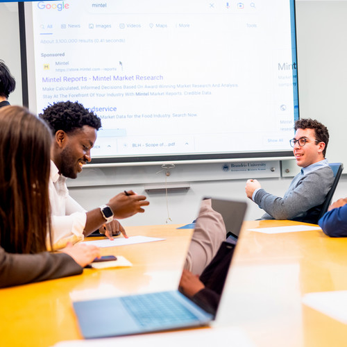 Students sit around a long table discussing their field projects.