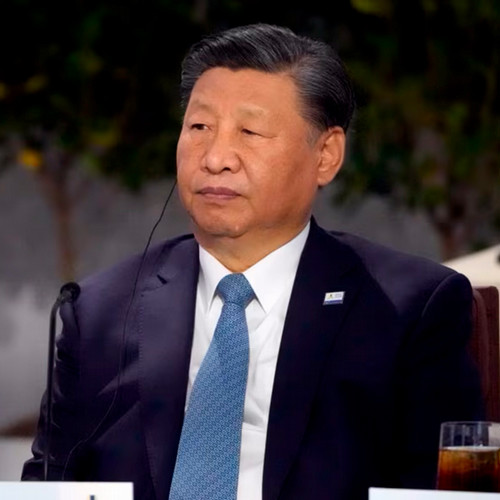 A picture of Xi Jinping in a suit listening at an international meeting with an earpiece translator.