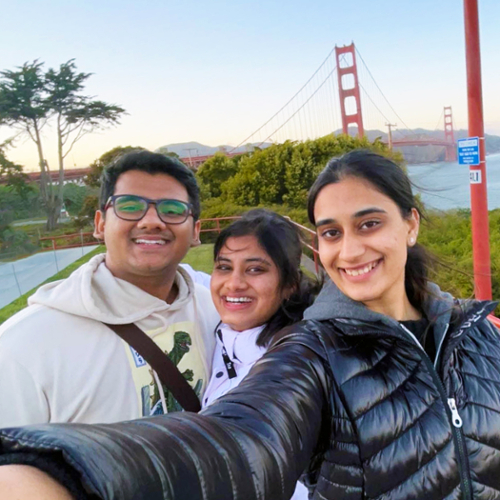Three students smile and pose with the Golden Gate Bridge in the background.