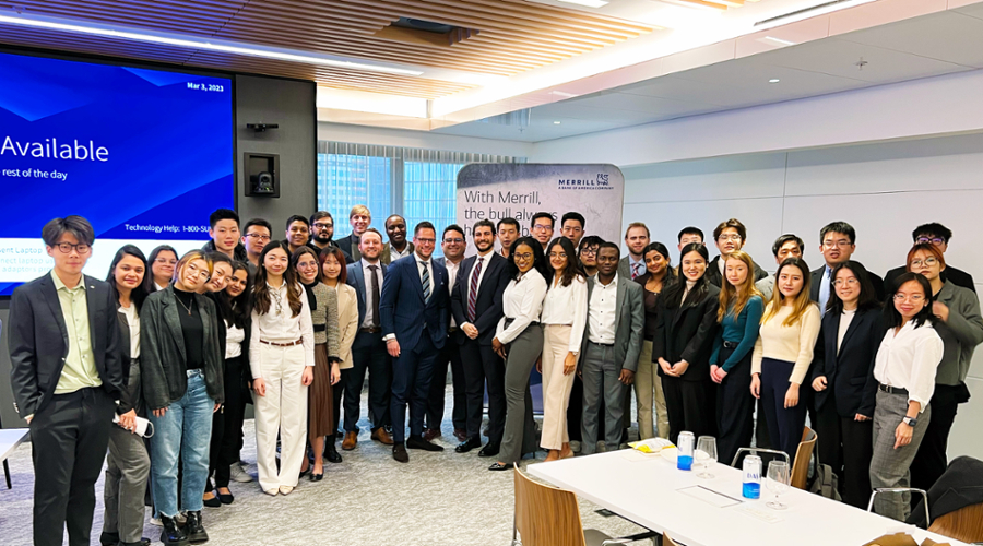 Students line up with alumni from Merrill Lynch in the company's office for a photo.