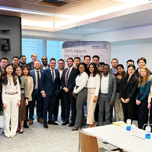 Students line up with alumni from Merrill Lynch in the company's office for a photo.