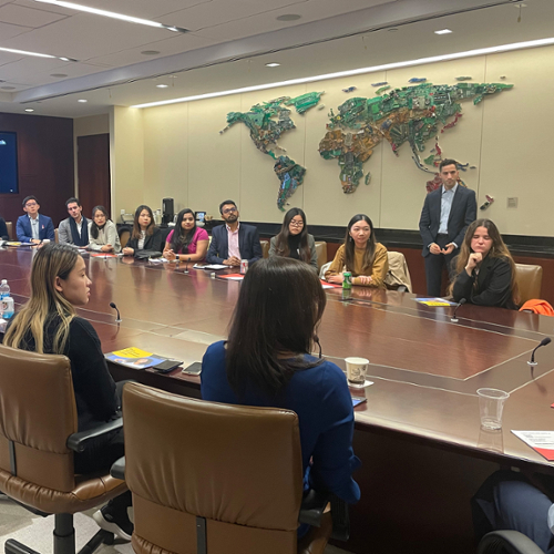 Students on the Industry Trek to BlackRock sit around a large conference table listening to finance professionals.
