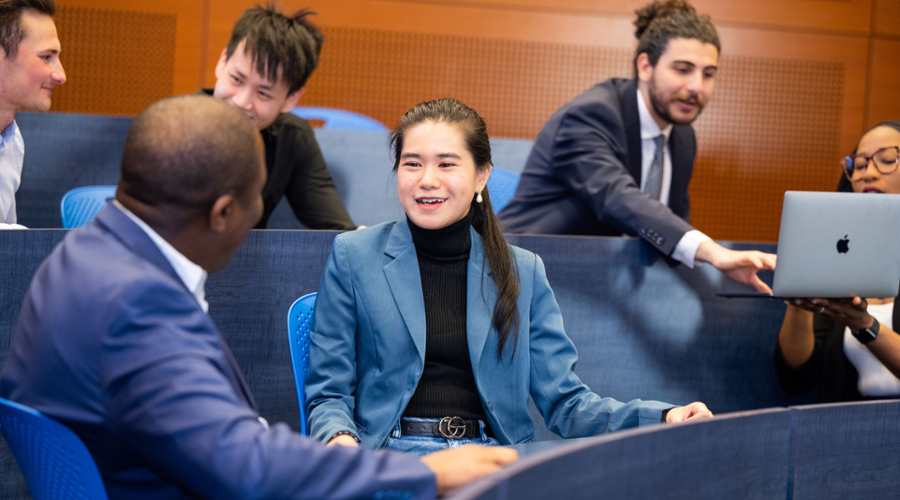 Students in professional attire chat in small groups.