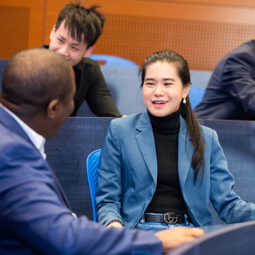 Students in professional attire chat in small groups.