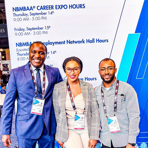 Three students pose in front of the National Black MBA Association backdrop.