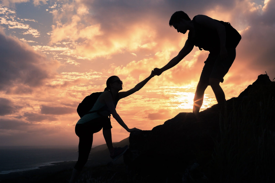 friends helping each other in a hike