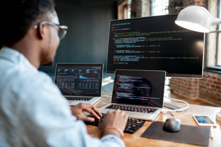 Person coding on two computers.