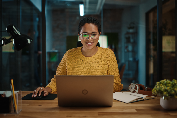 Person smiling at computer in the dark.