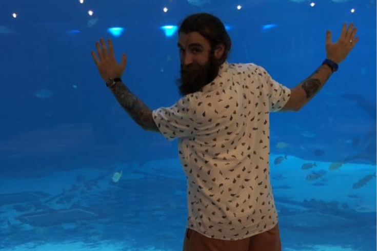 Dominic Lombardi standing in front of an aquarium tank with a toddler.