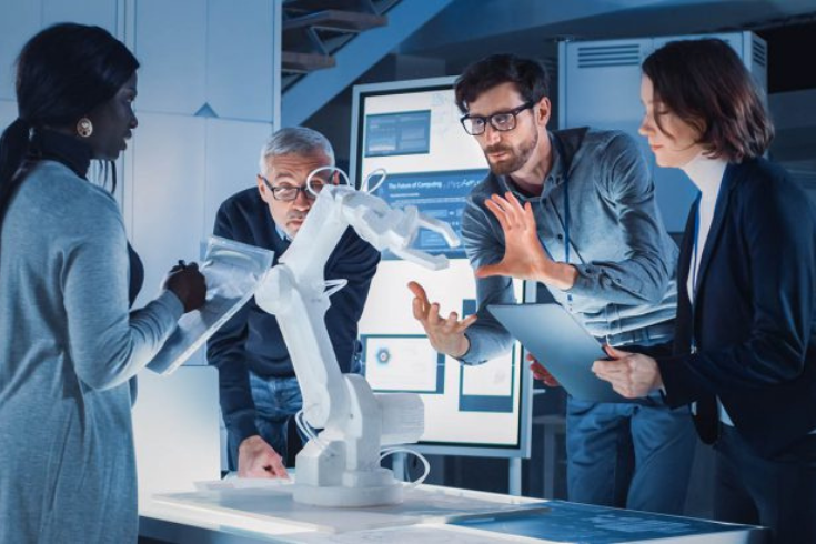 Four engineers standing around a robotic arm