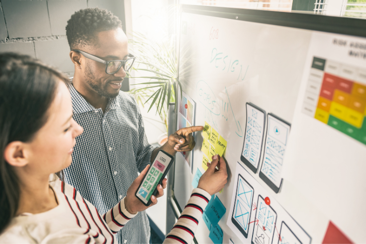 Two people working on a design using sticky notes.