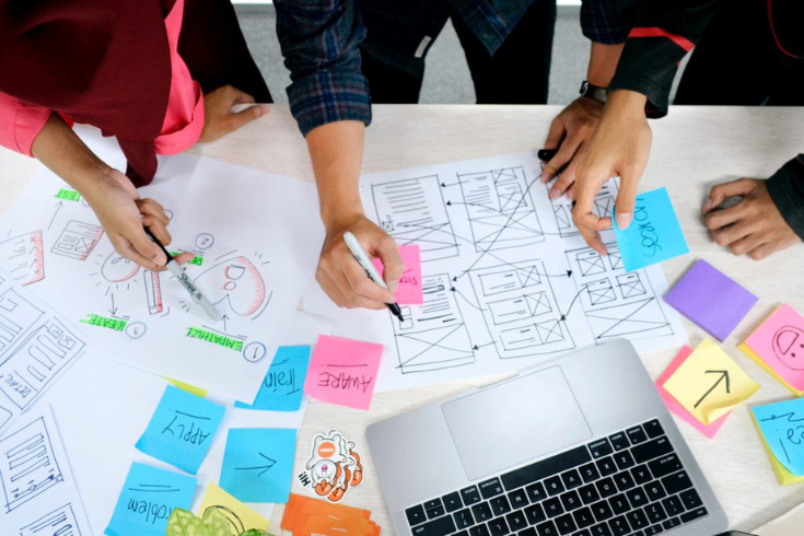 Several people sketching a design prototype on paper.