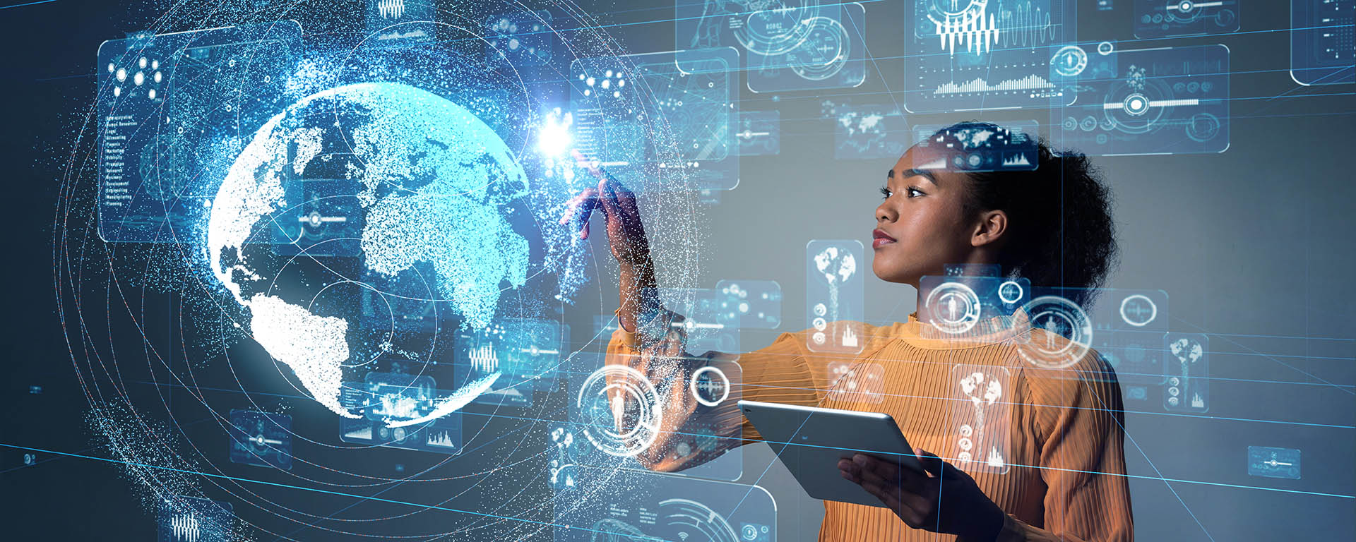 A student holding a tablet points to a 3D electronic diagram that surrounds her with spheres, the globe, charts and technical illustrations, all made of thin white lines on a blue background.