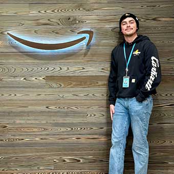 Brandon Lacy stands in front of a wall with the Amazon logo.