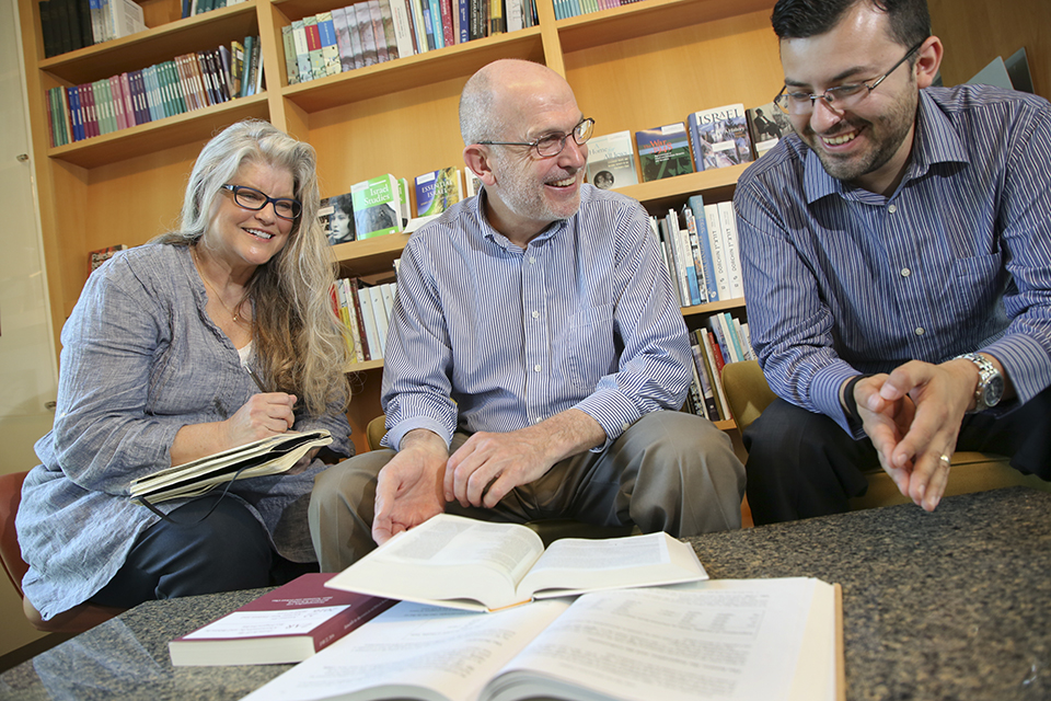 female and male faculty members review coursework with grad student