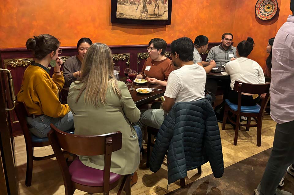 Groups of students sit around tables in a restaurant.