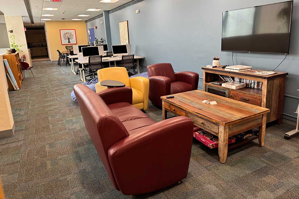 Graduate student lounge with sofas, chairs, big screen TV and computer workstations 