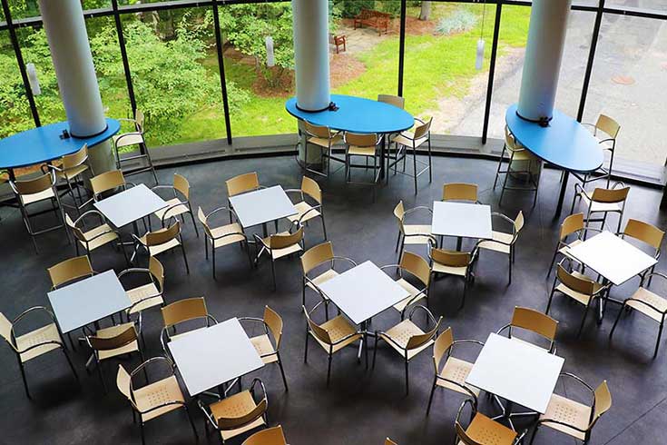 An atrium with glass walls and small tables and chairs