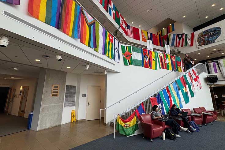 An atrium with chairs, tables, and various flags on the wall.