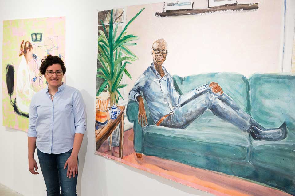 Sarah Valente stands in front of one of her paintings